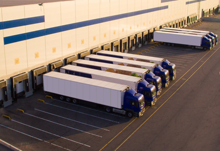 multiple tractor trailers lined up at warehouse dock doors