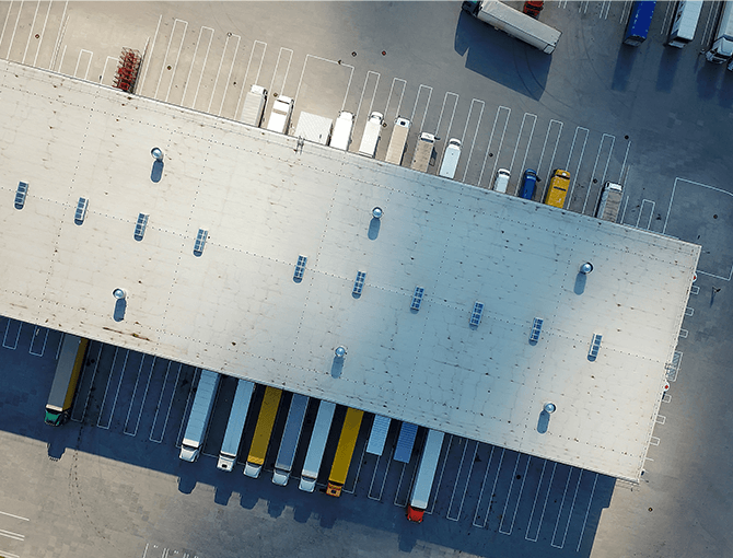 aerial view of multiple tractor trailers at warehouse dock doors on both sides for cross-docking operation