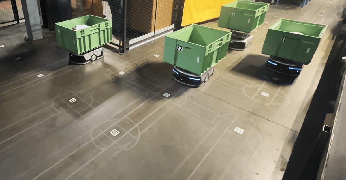 Autonomous guided vehicles (AGVs) traveling through a warehouse being guided by the FORTNA OptiSweep robotic solution