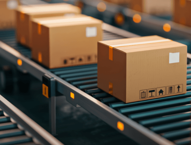 Cardboard boxes on a conveyor belt in a distribution warehouse, showcasing logistics and packaging processes | FORTNA