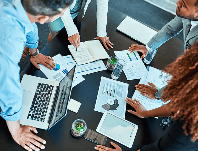 Group of professionals reviewing reports and data during a meeting - FORTNA
