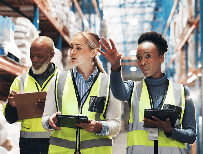 Supply chain team walking warehouse with tablets planning for change management - FORTNA